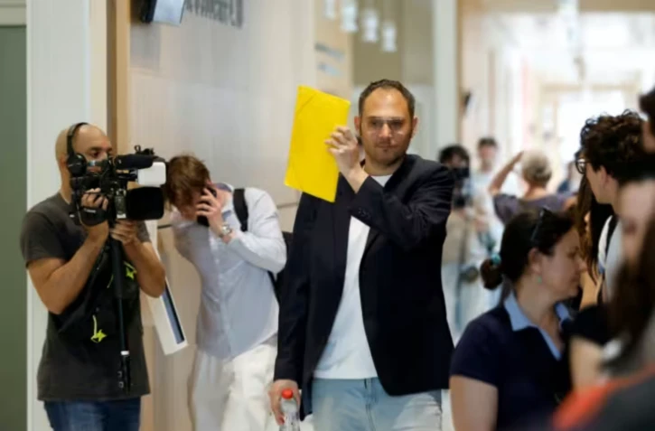 David G., animateur périscolaire, se cache le visage avec un dossier à son arrivée au tribunal où il doit être jugé pour agressions sexuelles sur neuf enfants, le 26 mai 2026 ( AFP / SIMON WOHLFAHRT )