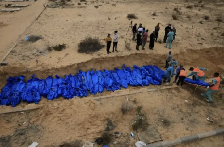 Des Palestiniens enterrent des corps dans une fosse commune à Khan Younès, dans le sud de la bande de Gaza, le 22 novembre 2023 ( AFP / Mahmud HAMS )