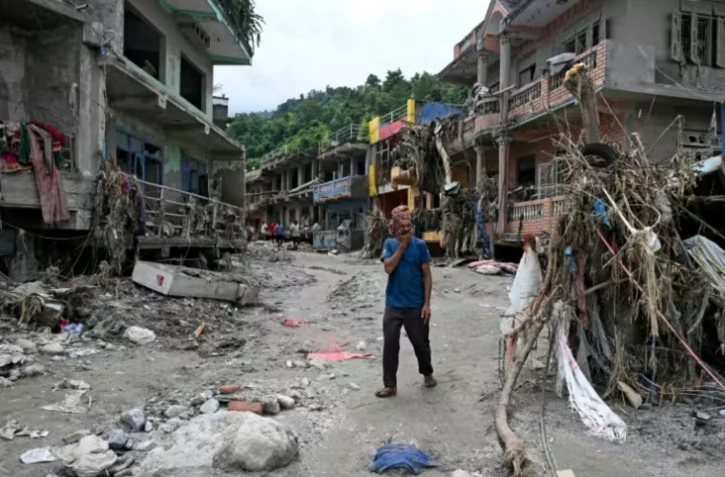 Un habitant passe devant des maisons endommagées par des crues soudaines à Devighat, dans le district de Nuwakot, le 31 août 2026 au Népal ( AFP / Arun SANKAR )
