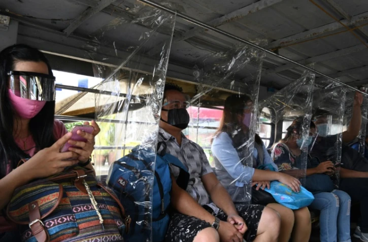 Les passagers d'un bus portant masque et écran facial dans un bus à Manille le 8 septembre 2020