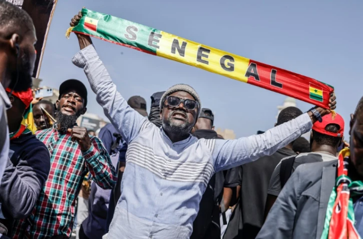Un homme brandit une banderole lors d'une manifestation contre le report de la présidentielle au Sénégal, à Dakar le 17 février 2024