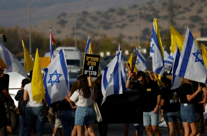 Des manifestants israéliens réclament une trêve à Gaza et la libération des otages, près du du kibboutz Amiad dans le nord d'Israël le 26 août 2025 avant une réunion du gouvernement israélien en soirée.
