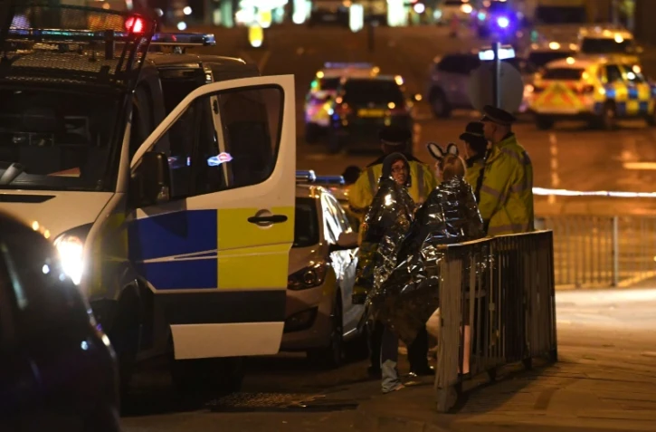 Des spectateurs près d'une salle de concerts à Manchester le 23 mai 2017, où une possible attaque terroriste a fait 19 morts et une cinquantaine de blessés