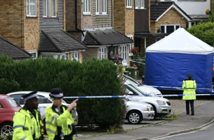 Des policiers devant une tente d'équipe médico-légale à Ashley Close à Bushey dans le Hertfordshire, au nord de Londres, le 10 juillet 2024, après un triple meurtre ( AFP / JUSTIN TALLIS )