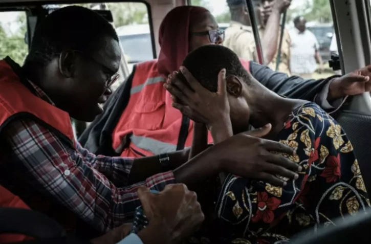 Un membre de la Croix-Rouge réconforte un fidèle de l'Eglise Internationale de Bonne Nouvelle secouru, près de la ville cotière de Malindi,le 25 avril 2023 au Kenya ( AFP / Yasuyoshi CHIBA )