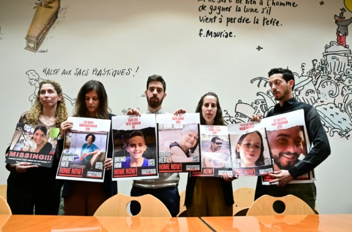 Des proches d'otages avec les photos des victimes, à droite le frère d'Elya Toledano, avec la photo d'Elya, à Paris le 31 octobre 2023