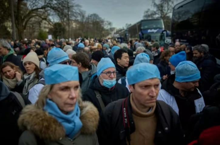 Des médecins embarquent dans des bus à Paris, pour un exil symbolique à Bruxelles, dans le cadre d'un mouvement de protestation, le 11 janvier 2026 ( AFP / Kiran RIDLEY )