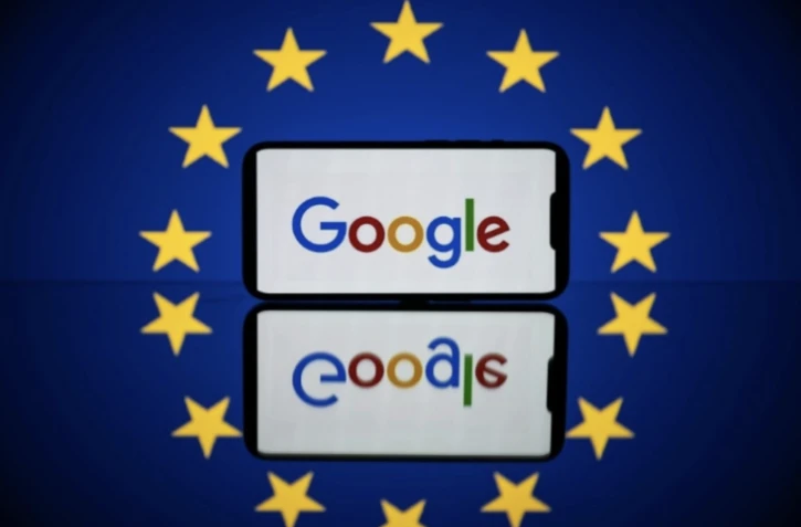 Le logo de Google sur un téléphone devant un drapeau européen. Photo prise le 27 avril 2023 à Toulouse ( AFP / Lionel BONAVENTURE )