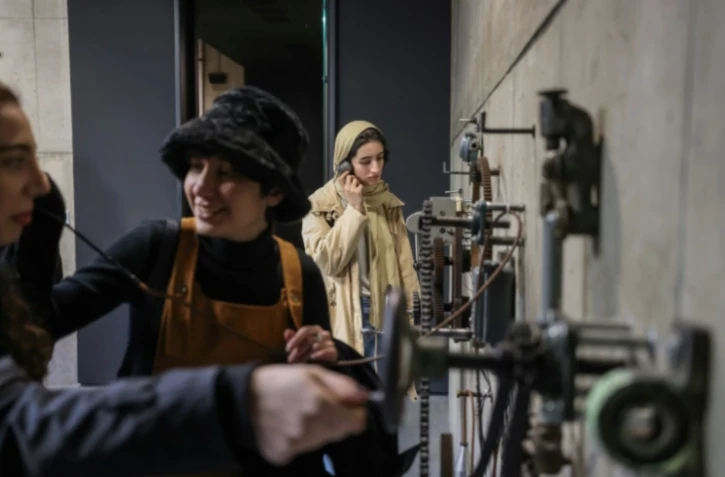 Des visiteurs écoutent de vieux enregistrements dans une exposition à Téhéran, le 4 février 2025 ( AFP / ATTA KENARE )