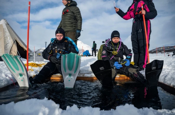 Des plongeurs participent à un stage scientifique de plongée polaire, le 14 mars 2026 sur le lac de Kilpisjärvi, à l'extrême nord-ouest de la Finlande