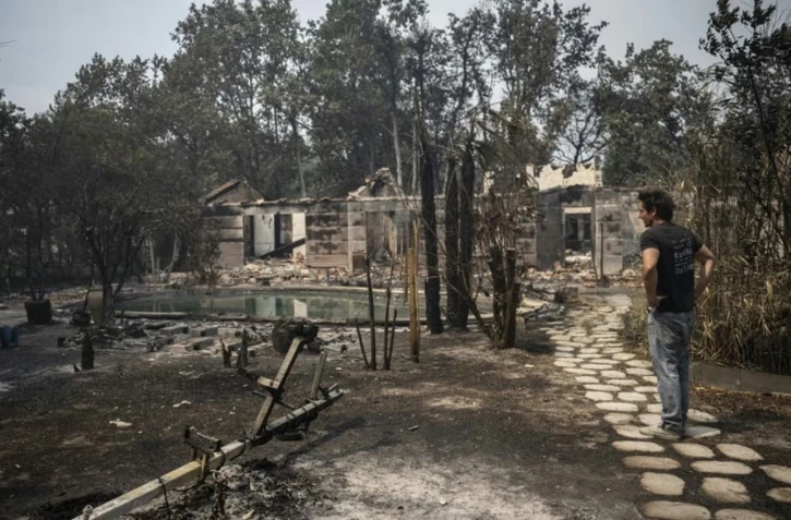 Un habitant inspecte les ruines des maisons du Porge (Gironde), dévastées par les flammes, le 26 juillet 2026. (JULIEN DE ROSA / AFP)