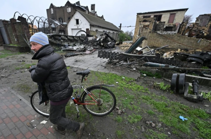 Un homme passe à côté d'un blindé russe et d'un bâtiment détruits à Gostomel, près de Kiev, le 22 avril 2022
