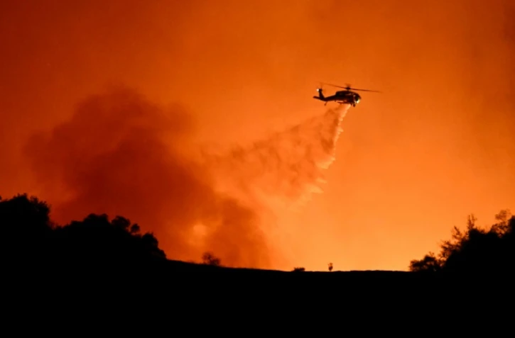 Un hélicoptère largue sa cargaison d'eau sur le feu qui ravage Los Angeles, le 10 janvier 2025
