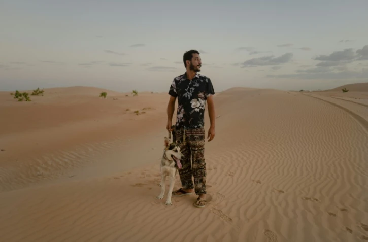 Ahmed Maham et son chien husky sibérien Kayo dans les dunes de Nouakchott, en Mauritanie, le 9 octobre 2024