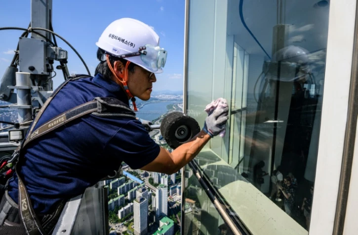 Seo Seung-ho nettoie les vitres du plus haut gratte-ciel de Séoul, le Lotte World Tower, depuis une "nacelle" suspendue par des câbles au 125e étage du bâtiment, le 4 juin 2024 à Séoul, en Corée du Sud