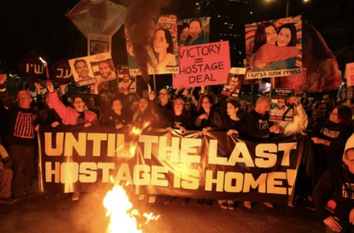 Des Israéliens tiennent des pancartes et allument des bougies lors d'une manifestation antigouvernementale appelant à agir pour obtenir la libération des otages israéliens à Gaza, devant le ministère de la Défense à Tel-Aviv le 18 janvier 2025 ( AFP / Jack GUEZ )