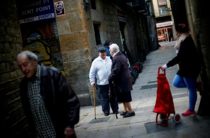 Le retraité Manuel Mourelo Gonzalez (c) discutent avec ses voisins dans le centre de Barcelone, en Espagne, le 17 février 2017
