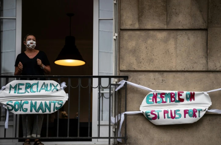 Une femme applaudit les soignants depuis le balcon de son appartement à Saint-Mandé, en banlieue parisienne, le 4 mai 2020 à20h