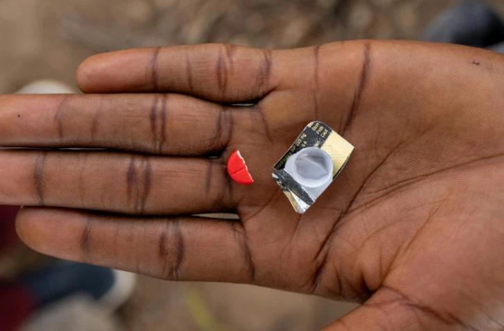 Un toxicomane tient la moitié d'un comprimé rouge à base de tapentadol à Abuja, le 24 février 2026 au Nigeria