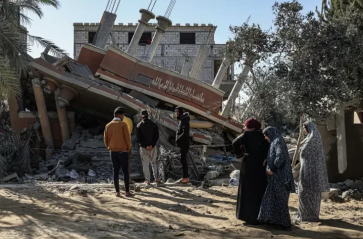 Des Palestiniens se tiennent devant les décombres d'une maison détruite par une frappe israélienne sur Khan Younès, dans le sud de la bande de Gaza, le 5 mars 2024 ( AFP / SAID KHATIB )