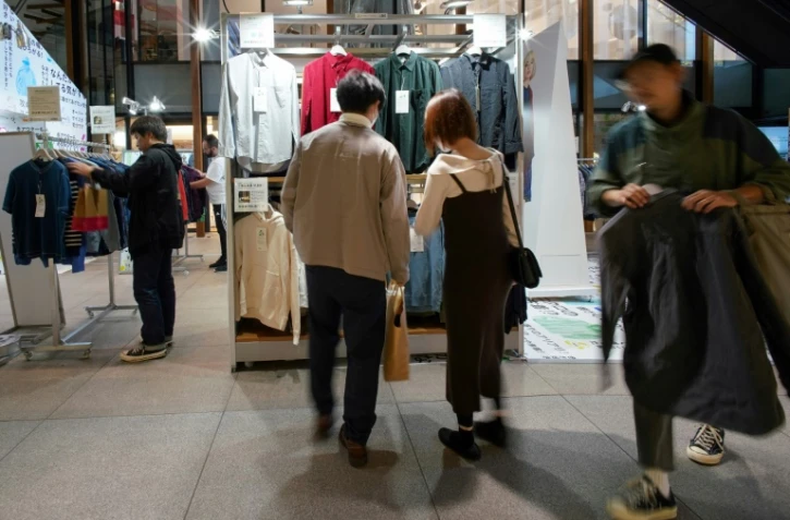 Des clients regardent des articles de seconde main de la marque japonaise Uniqlo vendus dans un pop-up store, le 17 octobre 2023 à Tokyo