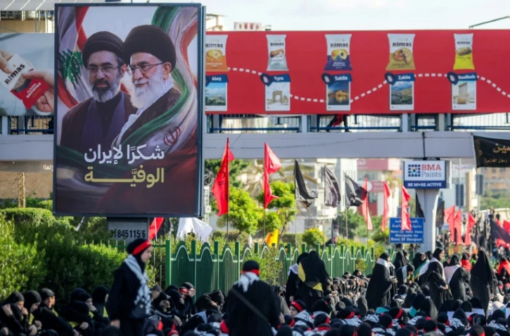 Une affiche représentant le défunt ayatollah Ali Khamenei et son fils l'actuel guide suprême iranien Mojtaba Khamenei est exposée alors que des fidèles chiites se rassemblent pour une procession funèbre, dans la banlieue sud de Beyrouth, le 26 juin 2026