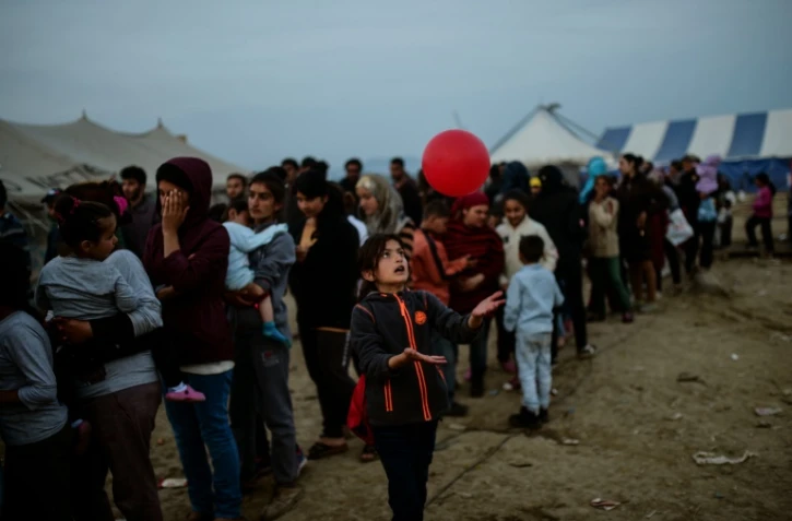 Une jeune migrante joue avec un ballon en attendant une distribution de nourriture dans le camp de migrants à la frontière gréco-macédonienne d'Idomeni, le 5 avril 2016