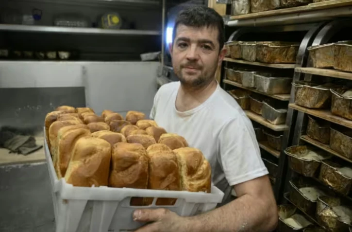 Le boulanger bénévole français Loïc Nervi tient un panier de pain fraîchement cuit dans sa boulangerie mobile afin de le distribuer aux résidents d'un logement temporaire pour les personnes qui ont perdu leur maison et les personnes déplacées à Borodianka, dans la région de Kiev, le 19 février 2026, dans le contexte de l'invasion russe de l'Ukraine. ( AFP / Genya SAVILOV )