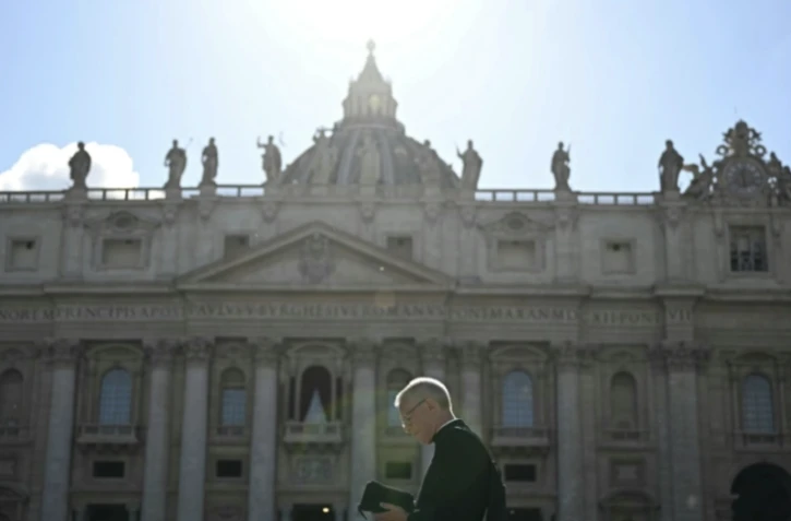Un prélat passe devant la basilique Saint-Pierre à la veille du début du conclave, place Saint-Pierre au Vatican, le 6 mai 2025 ( AFP / Gabriel BOUYS )