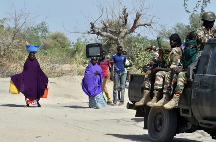 Des soldats nigériens passent devant des personnes qui fuient les islamistes de Boko Haram, le 25 mai 2015 à Malam Fatori