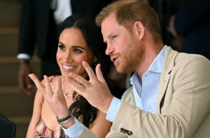 Le prince Harry (à droite), duc de Sussex, s'entretient avec son épouse Meghan Markle alors qu'ils assistent à un spectacle lors d'une visite au Centre national des arts de Bogota, le 15 août 2024. ( AFP / RAUL ARBOLEDA )