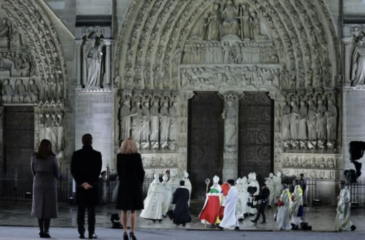 (g-d) La maire de Paris, Anne Hidalgo, le président Emmanuel Macron et son épouse Brigitte Macron devant Notre-Dame de Paris alors que l'archevêque de Paris, Mgr Ulrich, se dirige vers les portes de la cathédrale lors de la cérémonie pour sa réouverture officielle, le 7 décembre 2024 à Paris ( POOL / Christophe PETIT TESSON )