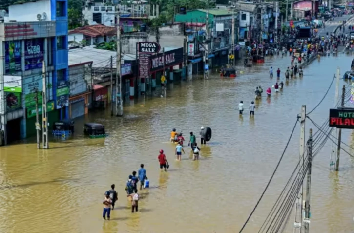 Des personnes traversent une rue inondée après de fortes pluies à Wellampitiya, près de Colombo, au Sri Lanka, le 30 novembre 2025 ( AFP / Ishara S. KODIKARA )