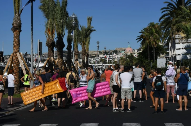 Des vacanciers traversent la Promenade des Anglais le 15 juillet 2016 à Nice au lendemain de l'attaque terroriste qui a fait 84 morts