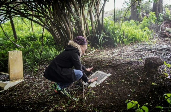 Une femme se recueille devant une plaque commémorative sur le site où sont enterrés des dépouilles d'esclaves à Jamestown, sur l'île britannique de Sainte-Hélène, le 18 octobre 2017