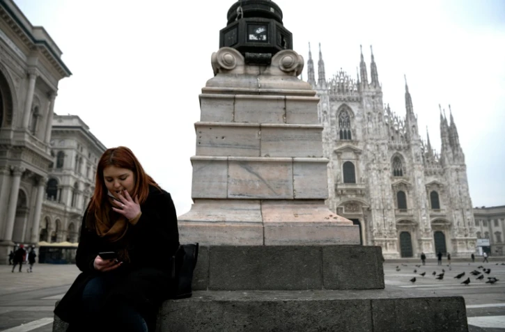 Une femme fume une cigarette sur la place du Duomo, le 19 janvier 2021 à Milan