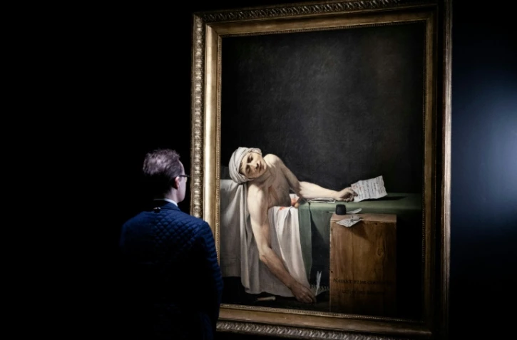 Un visiteur devant le tableau "La mort de Marat" (également connu sous le nom de "Marat Assassiné") du peintre français Jacques-Louis David, le 14 octobre 2025 au musée du Louvre à Paris