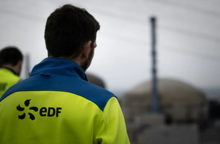 Des employés d'EDF en face d'une coupole de la centrale nucléaire de Flamanville dans la Manche, le 25 avril 2024
