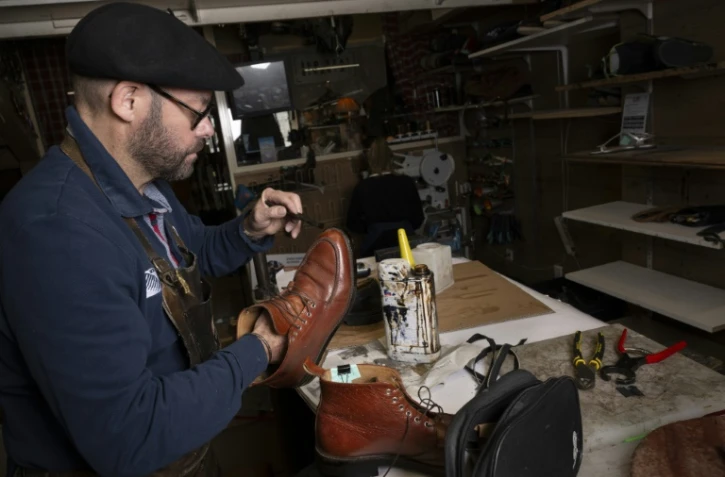 Le maître artisan cordonnier Thierry Hoo cire des chaussures qu'il a réparées dans la cordonnerie familiale "A la ville à la montagne", le 8 novembre 2023 à Paris