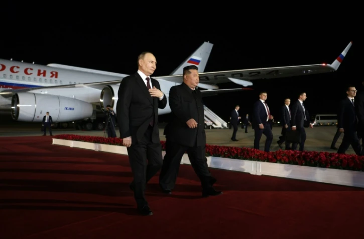 Le dirigeant nord-coréen Kim Jong Un (d) marche au côté du président russe Vladimir Poutine lors d'une cérémonie de bienvenue à l'arrivée de ce dernier à l'aéroport de Pyongyang, tôt le 19 juin 2024