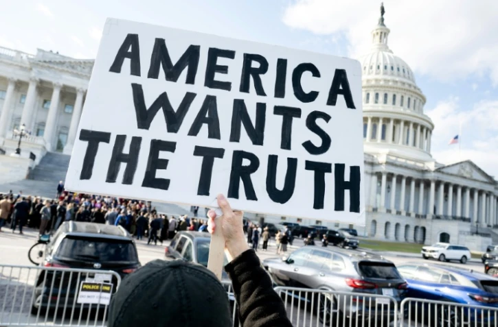 Un manifestant tient une pancarte "l'Amérique veut la vérité", demandant la publication des documents liés à l'affaire Epstein, devant le Capitole de Washington, siège du Congrès américain, le 12 novembre 2025
