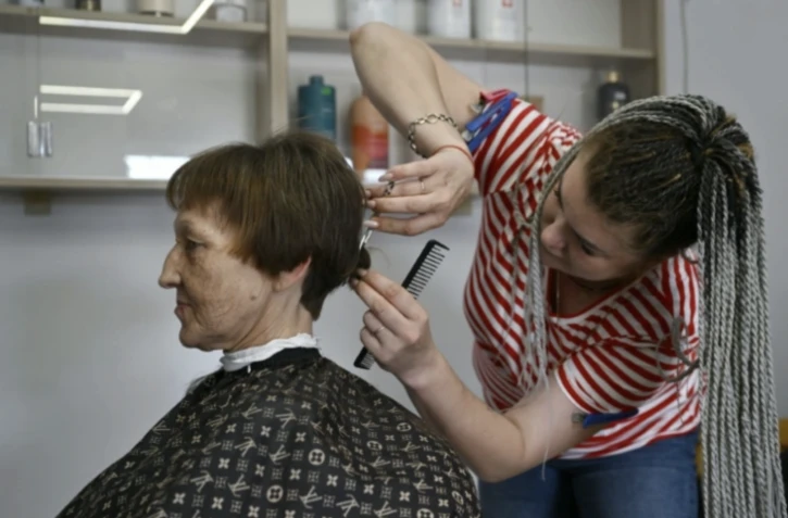 Marina Skromnaïa (g) se fait couper les cheveux dans un salon de beauté à Pokrovsk, dans la région de Donetsk, le 21 septembre 2024 en Ukraine ( AFP / Genya SAVILOV )