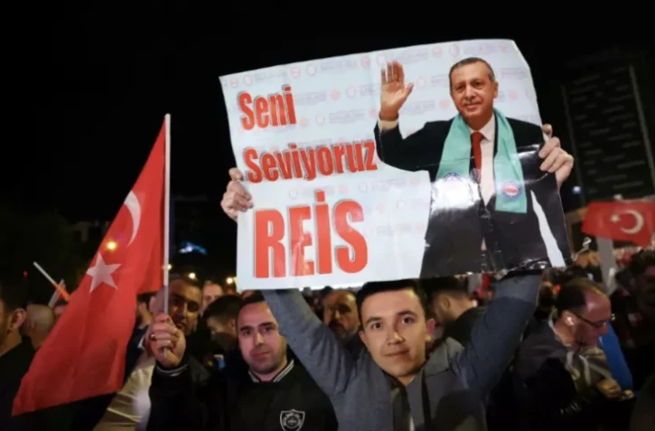 Un soutien du président turc sortant Tayyip Erdogan tient une affiche sur laquelle on peut lire "Nous t'aimons, Reis" pendant un rassemblement devant son parti, l'AKP, à l'issue du premier tour des élections générales à Ankara, le 15 mai 2023 ( AFP / Adem ALTAN )