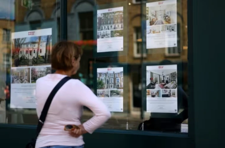 Une passante regarde les annonces immobilières à l'entrée d'une agence à Londres le 18 juin 2026 ( AFP / Toby Shepheard )