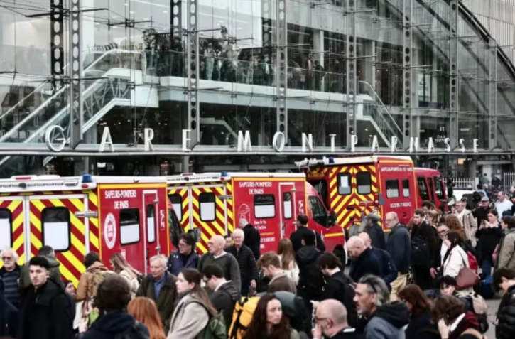 Des pompiers et passagers devant la Gare Montparnasse, partiellement évacuée après le tir d'un policier contre un hommme armé d'un couteau le 14 novembre 2025 à Paris ( AFP / Thibaud MORITZ )