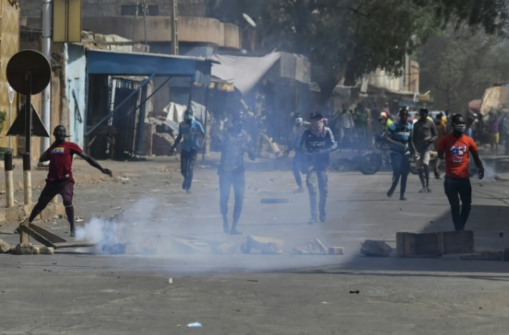 Des manifestants proches de l'opposition au Niger jettent des pierres lors de heurts avec la police à Niamey, le 24 février 2021