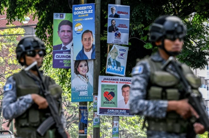 Des soldats guatémaltèques patrouillent près des affiches des candidats aux élections générales à Guatemala le 22 juin 2023