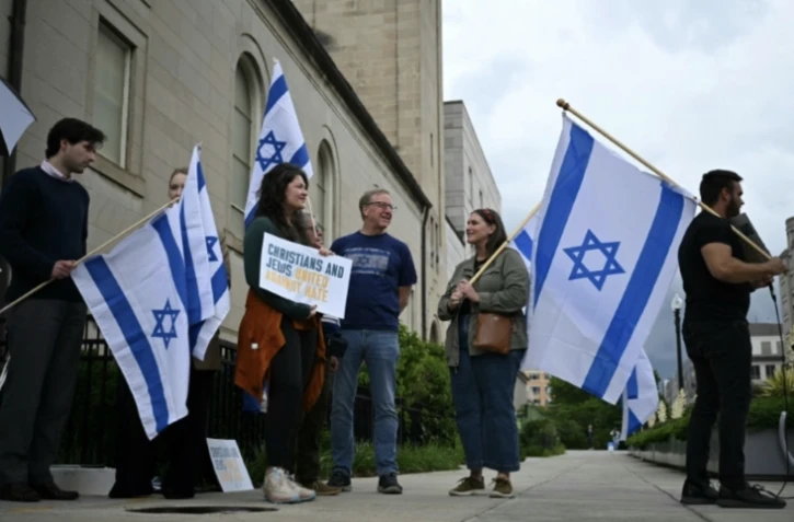 Des personnes brandissent des pancartes et des drapeaux israéliens en signe de soutien devant le Musée juif de Washington, aux Etats-Unis, le 22 mai 2025 ( AFP / Drew ANGERER )