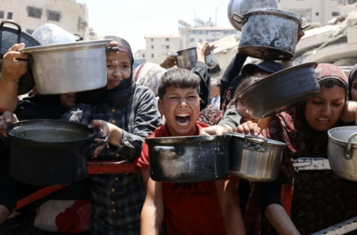 Des Palestiniens se pressent lors d'une distribution de soupe aux lentilles, à Gaza-ville le 27 juillet 2025 ( AFP / Omar AL-QATTAA )