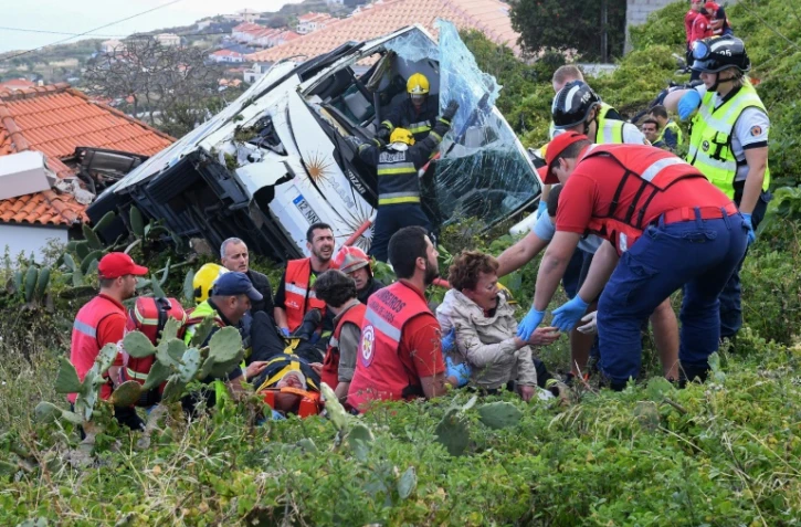 Les pompiers aident des victimes de l'accident de car qui a tué 29 personnes à Madère à sortir de l'épave, le 17 avril 2019